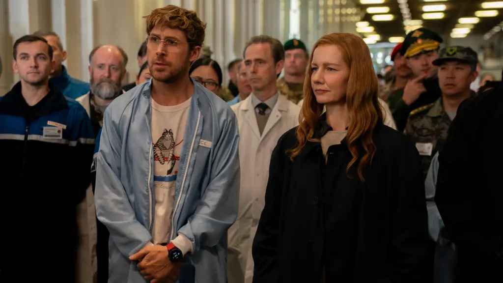 Ryan Gosling dan Sandra Hüller berdiri berdampingan dalam situasi cemas saat rapat dengan ilmuwan top NASA di PROJECT HAIL MARY.