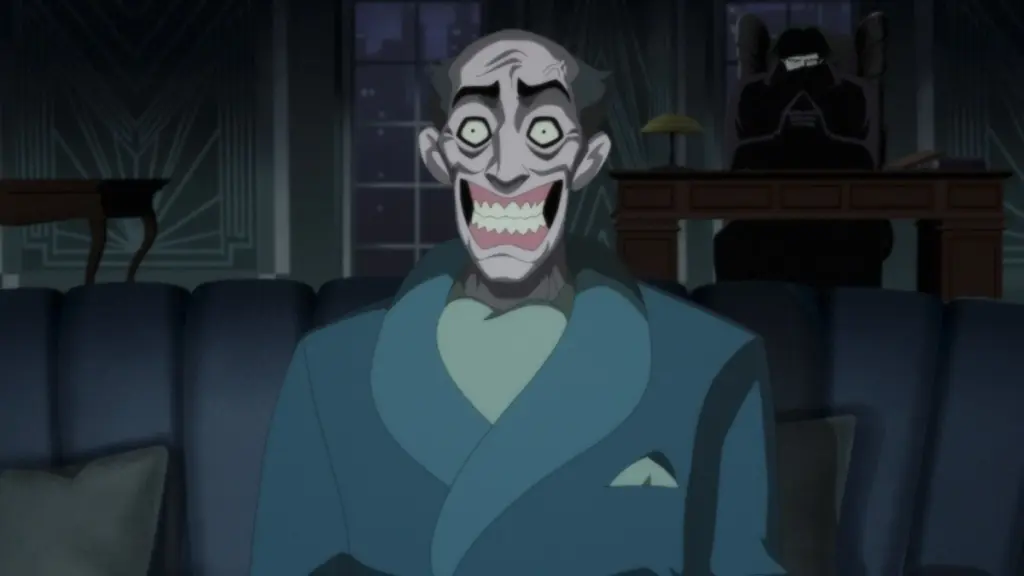 Seorang pria korban senyum lebar duduk beku di kursi sementara versi Noir dari Joker duduk di bayangan di belakangnya di BATMAN: CAPED CRUSADER Season 2.